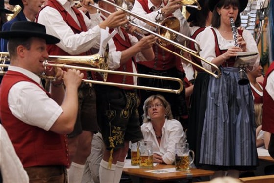 A woman sits between musicians during the second day of the Oktoberfest beer festival on Sunday in Munich, Germany.